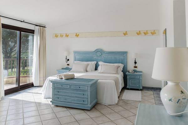 Schlafzimmer im Abi d'Oru Beach Hotel & Spa mit blauen Möbeln und einem Balkonblick.