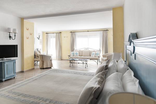 Ein modernes Schlafzimmer im Abi d'Oru Beach Hotel & Spa mit einem großen Bett, gelben Wänden und einem Fernseher.