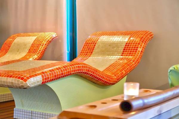 Zwei orange und weiße geflieste Loungesessel im Wellnessbereich des Louros Beach Hotel & Spa.