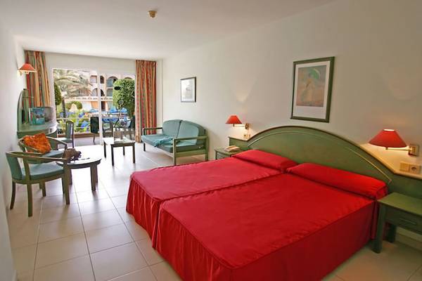 Schlafzimmer im Mirador Maspalomas Hotel mit zwei roten Betten, grünen Möbeln und einer Aussicht auf den Garten.