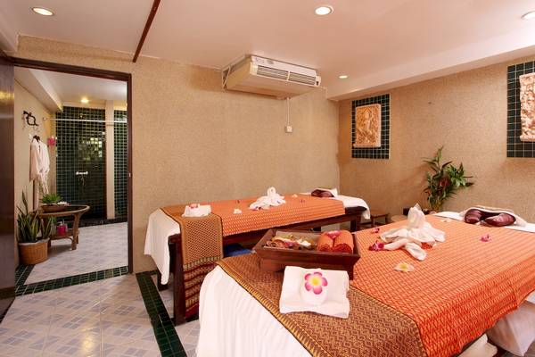 Massageraum im Best Western Phuket Ocean Resort mit zwei Betten, Kissen und Pflanzen.