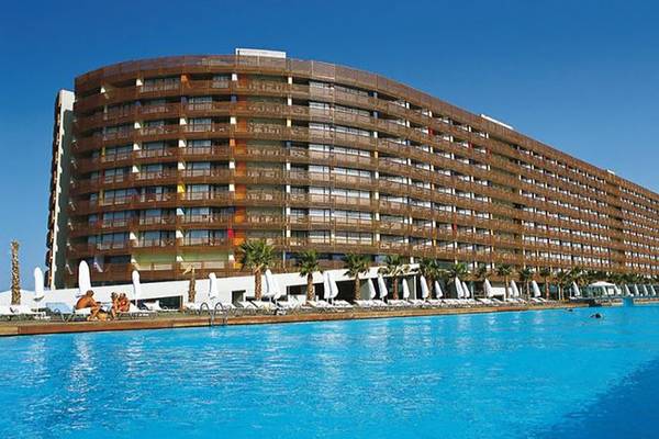 Außenansicht des Nirvana Cosmopolitan Hotels mit großem Swimmingpool und Sonnenliegen.