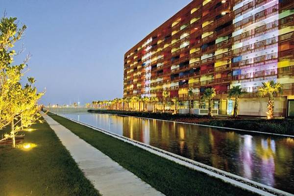 Außenansicht des Nirvana Cosmopolitan Hotels bei Nacht mit farbigen Lichtern und Wassergraben