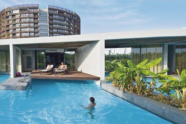 Schwimmbad und Loungebereich im Nirvana Cosmopolitan Hotel mit zwei Personen auf Liegen.