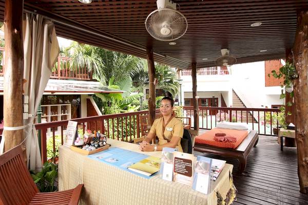 Empfangsdame im Best Western Phuket Ocean Resort sitzt am Empfangstisch auf der Terrasse.