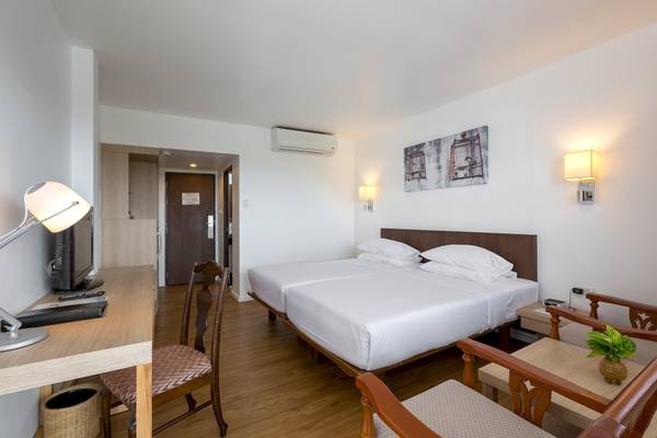 Doppelzimmer im Best Western Phuket Ocean Resort mit zwei Betten, Schreibtisch und Lampe.