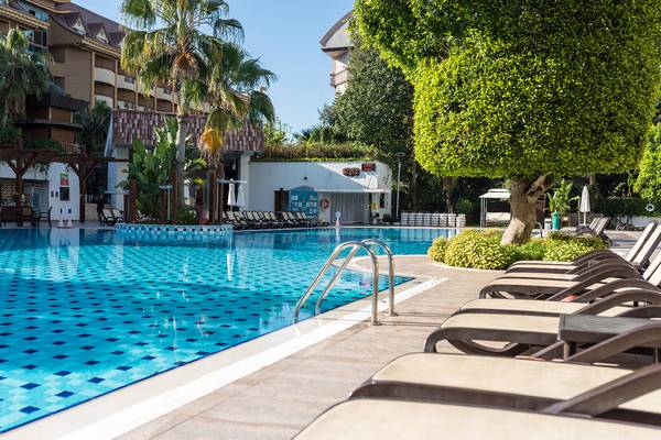Außenpool des Port Side Resort Hotels mit Liegestühlen und Sonnenschirmen.