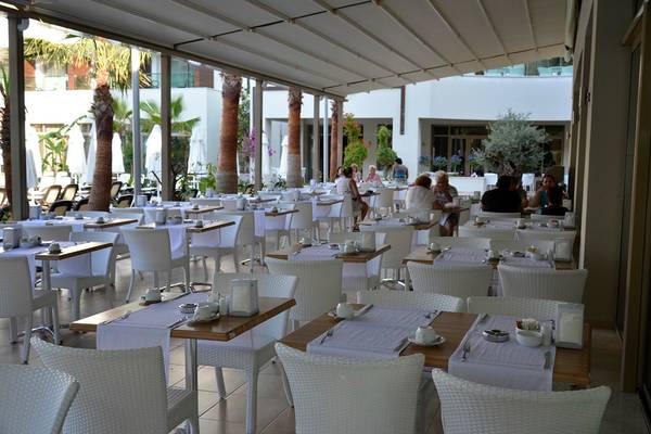 Restaurantterrasse im Port Side Resort mit weißen Tischen und Stühlen.