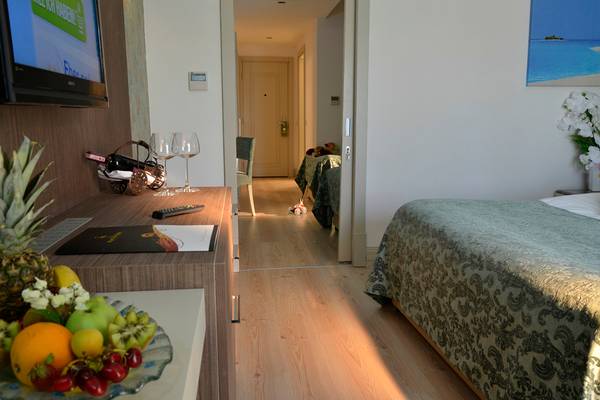 Ein Hotelzimmer mit einem Bett, einem Tisch und einer Flasche Wein.