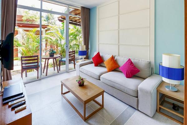 Wohnzimmer des Apsara Beachfront Resort und Villa mit großer Couch und Tisch.