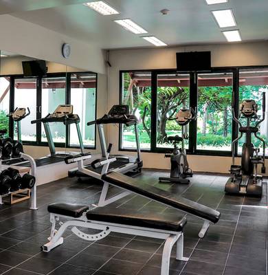 Fitness Center im Apsara Beachfront Resort und Villa mit Geräten und Fenstern.