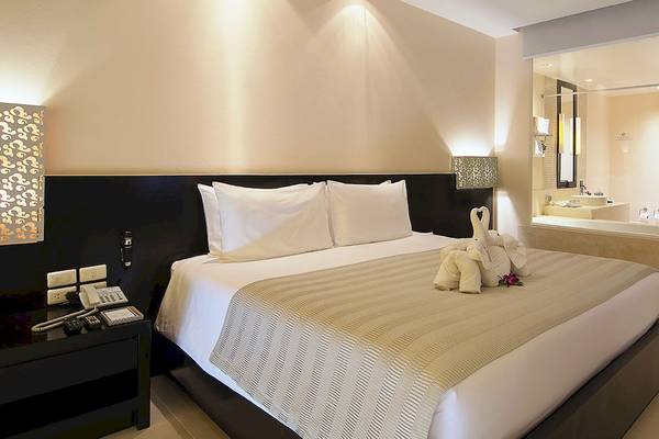 Hotelzimmer im Apsara Beachfront Resort and Villa mit Bett, Kissen, Elefantenfiguren und Nachttisch.