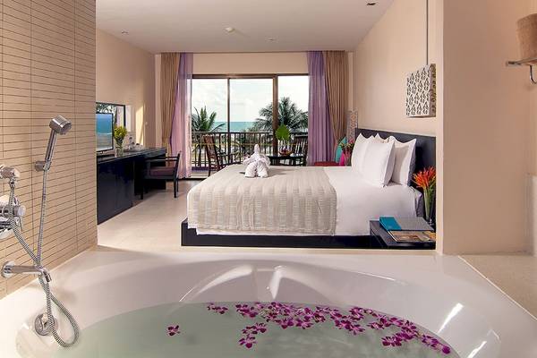 Suite-Innenraum im Apsara Beachfront Resort und Villa mit Badewanne, Bett und Meerblick.