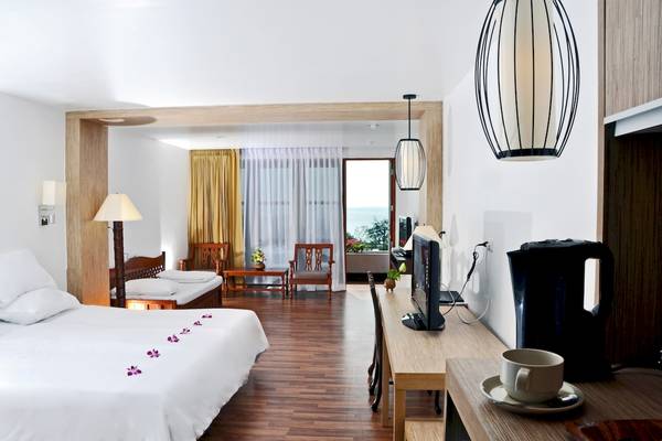 Innenansicht eines Zimmers im Best Western Phuket Ocean Resort mit Doppelbett, Fernseher und Blick auf den Garten.
