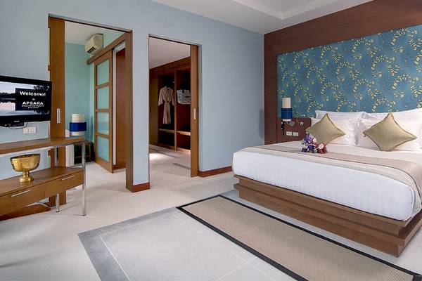 Das elegante Schlafzimmer im Apsara Beachfront Resort und Villa mit blauen Wänden und Holzmöbeln.