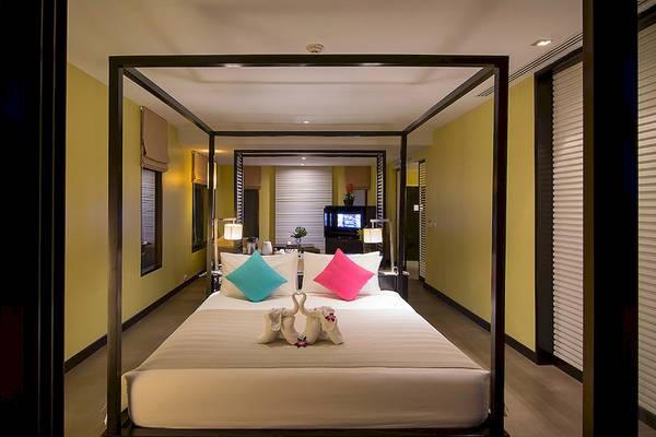 Schlafzimmer im Apsara Beachfront Resort und Villa mit Himmelbett, zwei Kissen und Dekor.