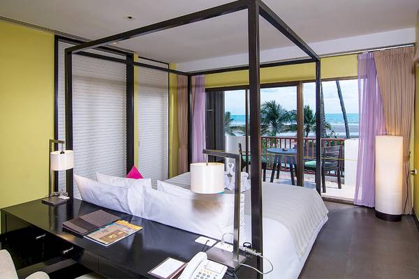 Schlafzimmer im Apsara Beachfront Resort und Villa mit einem Baldachin-Bett, einem Schreibtisch und einem Balkon mit Blick auf das Meer.