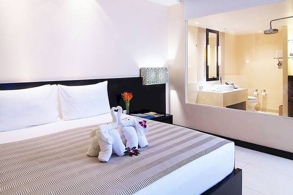 Hotelzimmer im Apsara Beachfront Resort und Villa mit Bett, zwei Elefantenkissen und Badezimmerspiegel im Hintergrund.