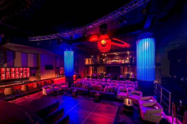 Lounge-Bereich im Hotel mit blauen und roten Lichtern, Sofas und einer Bar.