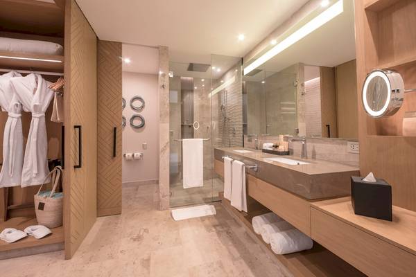 Ein modernes Badezimmer mit einer Glasdusche und einem Doppelwaschbecken, umgeben von Holzmöbeln und weißen Handtüchern.