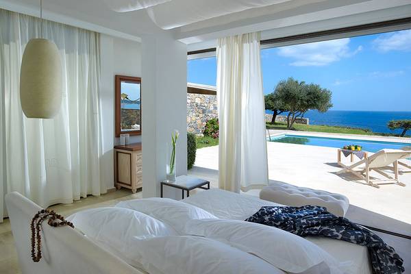 Schlafzimmer im St. Nicolas Bay Resort Hotel & Villas mit Blick auf das Meer und einen Swimmingpool.