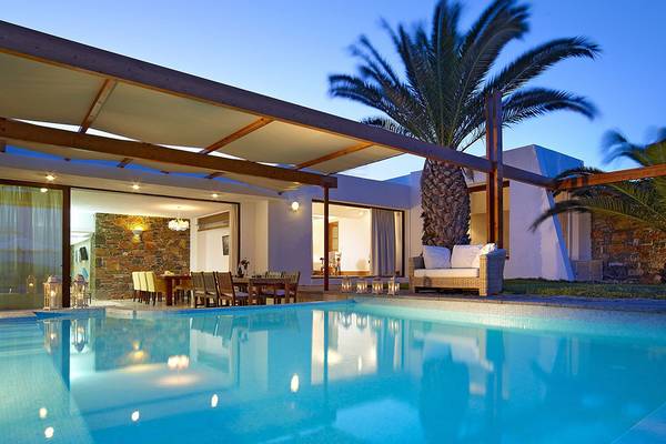 Au ßenbereich des St. Nicolas Bay Resort Hotel & Villas mit Swimmingpool, Esstisch und Loungesofa.