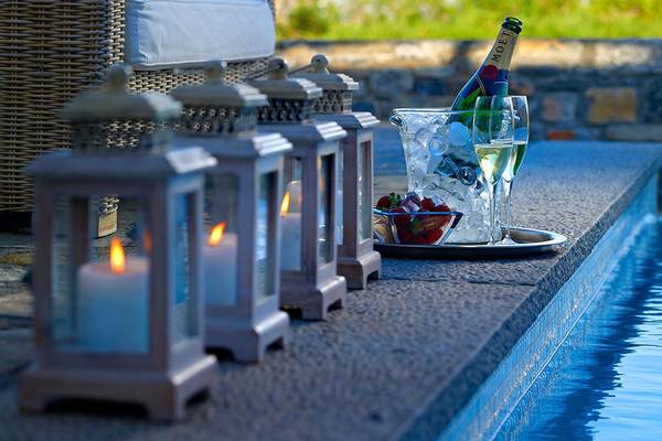 Poolrand mit brennenden Kerzen und Champagnerflasche