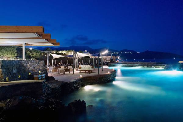 St. Nicolas Bay Resort Hotel & Villas bei Nacht mit beleuchtetem Pool und Loungebereich.