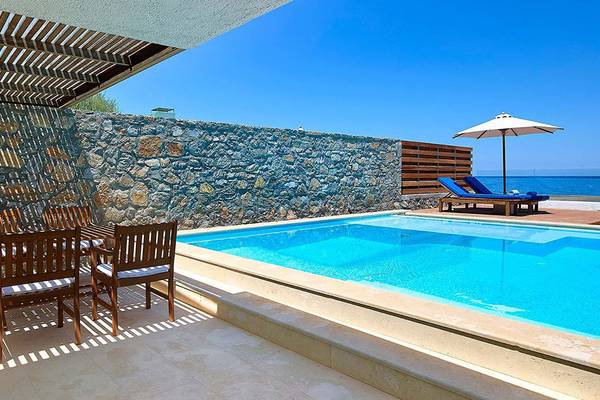 Pool-Terrasse mit Holztisch und Sonnenliegen im St. Nicolas Bay Resort Hotel & Villas