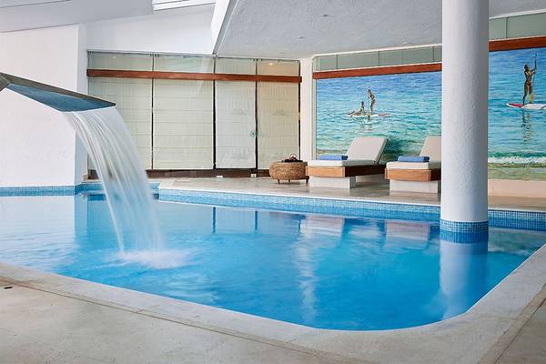 Innenpool des St. Nicolas Bay Resort Hotel & Villas mit Wasserfall und Liegebereich