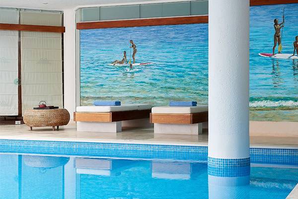 Poolbereich im St. Nicolas Bay Resort Hotel & Villas mit Strandmural und Loungesofas