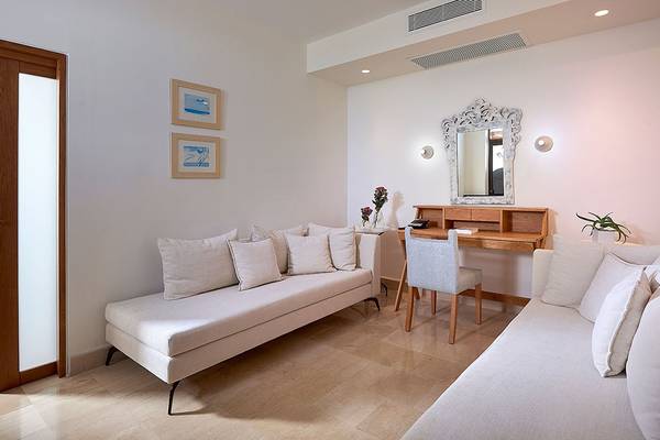 Innenraum des St. Nicolas Bay Resort Hotel & Villas mit zwei weißen Sofas, einem Schreibtisch und einem Spiegel.