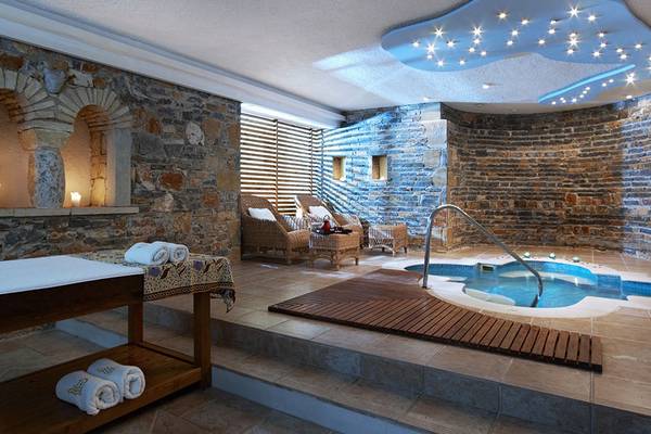 Spa-Bereich im St. Nicolas Bay Resort Hotel & Villas mit Steinwänden und einem Whirlpool.