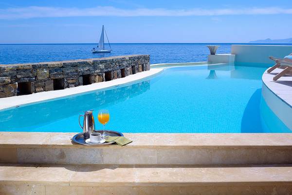 Außenpool des St. Nicolas Bay Resort Hotel & Villas mit Blick auf das Meer und eine Segelyacht.