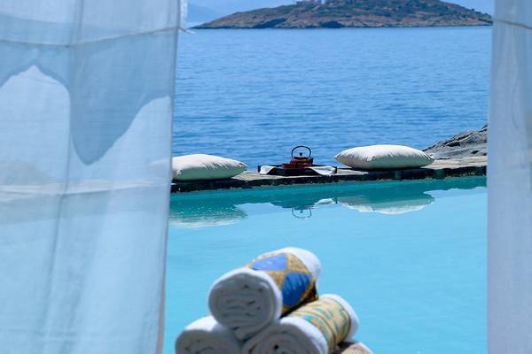 Poolblick aus dem Hotelzimmer im St. Nicolas Bay Resort Hotel & Villas mit zwei Kissen, einem roten Teekessel und gerollten Handtüchern.