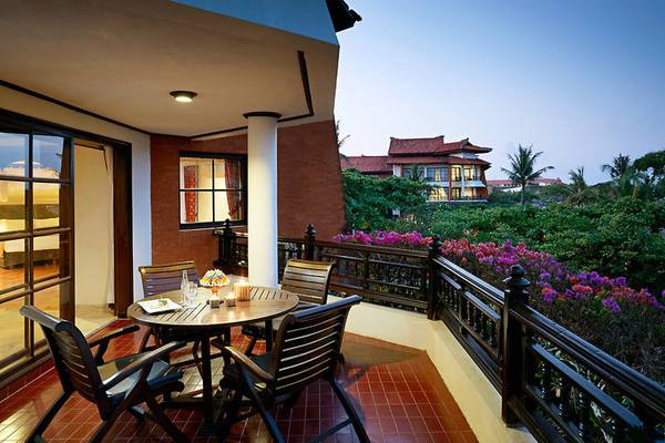Balkon des Sol Benoa Bali Hotels mit Tisch, Kerzen und Blick auf Pflanzen.