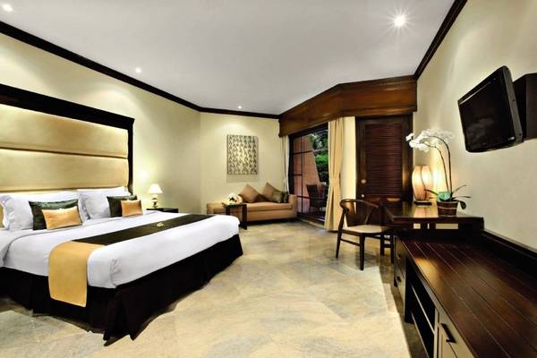 Schlafzimmer im Sol Benoa Bali Hotel mit großem Bett, Sofa und Fernseher.