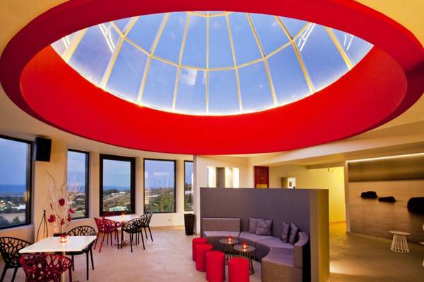 Innenraum des Kipriotis Panorama Suites mit roter Halbkuppeldecke und Fenstern, die auf die Aussicht blicken.