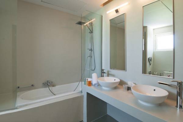 Badezimmer im Kipriotis Panorama Suites mit Badewanne, Waschbecken und Spiegeln.