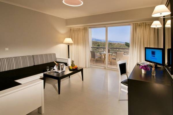 Innenansicht eines Zimmers im Kipriotis Panorama Suites Hotel mit Blick auf einen Balkon.