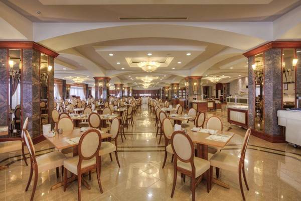 Innenansicht des Restaurants im Kipriotis Panorama Suites Hotel mit gedeckten Tischen und Stühlen.