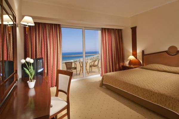Hotelzimmer im Kipriotis Panorama Suites mit Meerblick, Bett, Schreibtisch und Balkon.