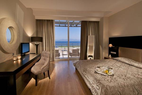 Innenansicht des Kipriotis Panorama Suites Hotels mit einem Bett und einem Schreibtisch.