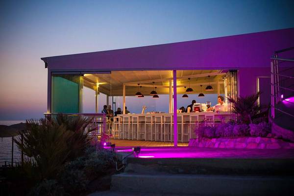 Terrasse des Royal Blue Resorts bei Nacht mit violetten Lichtern und Gästen.