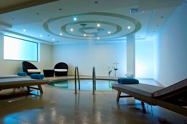 Spa-Bereich im Royal Blue Resort mit zwei Lounge-Liegen und einem Pool.