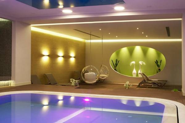 Innenpool des Kipriotis Panorama Suites Hotels mit Lounge-Bereich und grüner Wand.