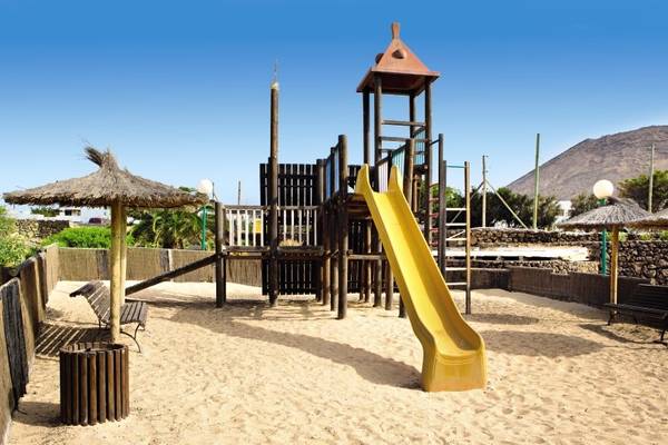 Spielplatz im Freien im Hotel SBH Royal Monica mit gelber Rutsche und Strohdach