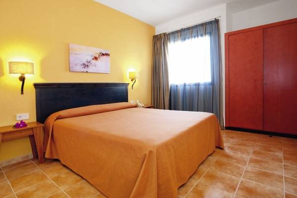Hotelzimmer im SBH Royal Monica mit gelben Wänden, einem Doppelbett, Nachttischen und einem Schrank.