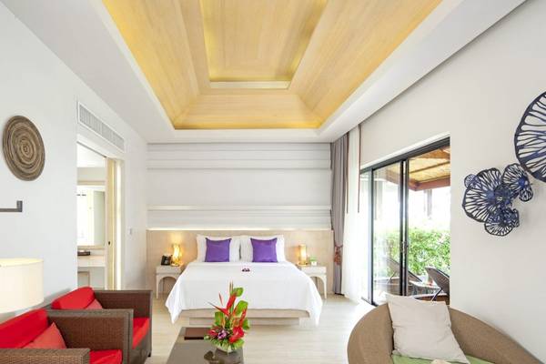 Suite-Innenraum im Beyond Resort Khao Lak mit Bett, Kissen, Lampen und Möbeln.
