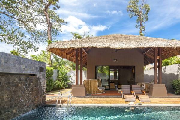 Poolseite der Beyond Resort Khao Lak mit einer Strohdach-Hutte und Sonnenliegen.